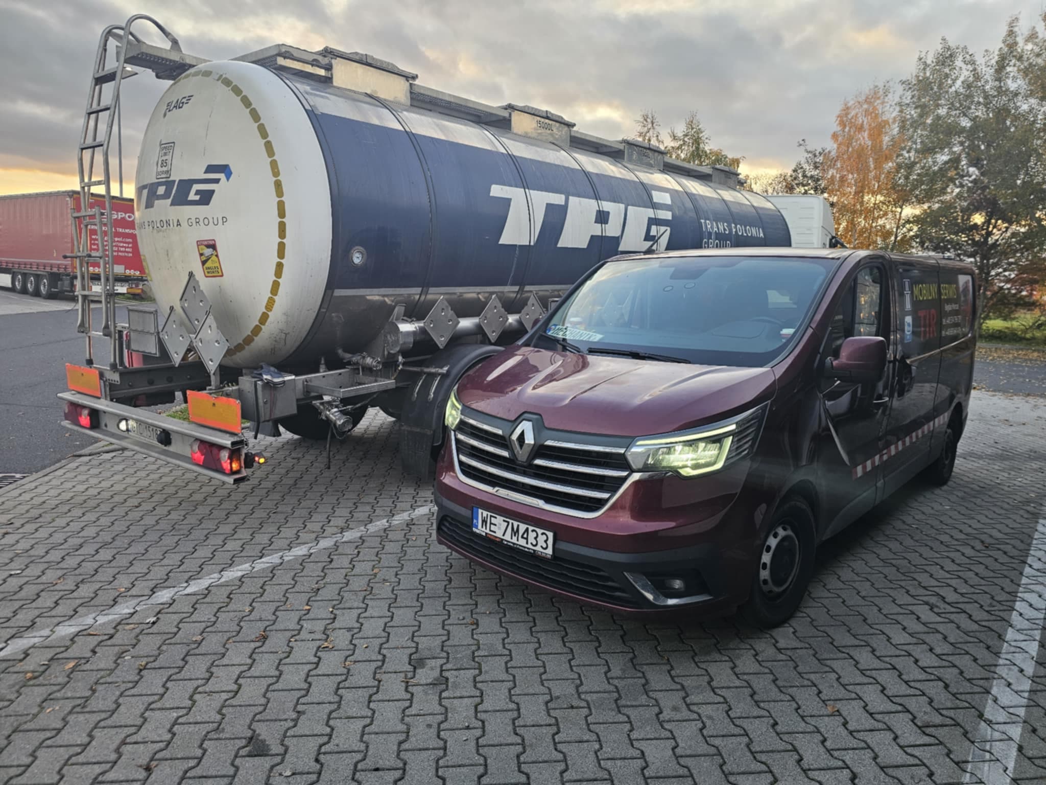 Samochód firmowy stojący obok ciężarówki z cysterną.